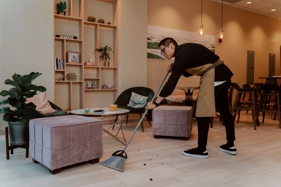 Un homme portant un masque se désinfecte les mains tout en travaillant sur un ordinateur portable à l'intérieur.